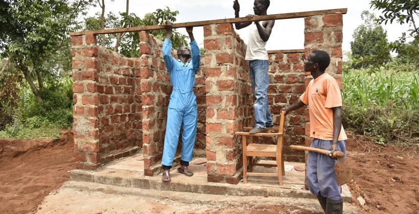 three men building a latrine in Kenya