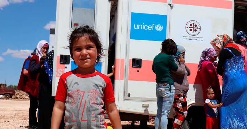 child standing in front of UNICEF mobile health unit