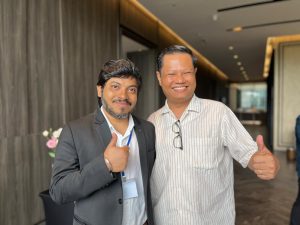 Two learning forum participants stand side by side, smiling and facing the camera, with their thumbs up. 